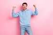 © deagreez - Photo of pretty lucky man wear blue hoodie screaming rising fists smiling isolated pink color background