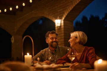 Wall Mural - Happy couple enjoys in glass of wine in evening on terrace.