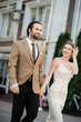 © LIGHTFIELD STUDIOS - happy bride in wedding dress looking at groom while holding hands on street.