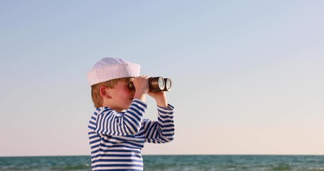 Wall Mural - Kid looking through spyglass. Summer vacation and travel concept. Slow motion