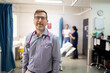 © Austockphoto - Smiling middle-aged male doctor  with a stethoscope around his  neck standing in the clinic