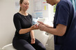 © Austockphoto - Health worker getting a blood sample from a woman using a blood lancet in the clinic