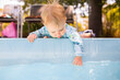 © Austockphoto - Young baby leaning over edge of inground swimming pool splashing in water – dangerous situation