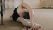© Framestock - Ballerina in training bodysuit sits on split near ballet barre in dance studio, stretches her leg and prepares for performance. Ballet dancer doing gymnastic exercises. Classical ballet dance school.
