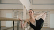 © Framestock - Adult woman in training bodysuit stands front of ballet barre in dance studio, stretches and prepares for performance. Graceful Ballet dancer doing gymnastic exercises. Classical ballet dance school.