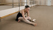 © Framestock - Female ballet dancer finished choreography rehearsal. Tired ballerina in training bodysuit takes off pointe shoes after stretching and gymnastic workout in dance studio. Classic ballet dance school.