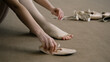© Framestock - Beautiful ballet dancer sits on floor near pointe at dance studio and puts on ballet shoes before choreography lesson. Ballerina prepares for performance. Classical ballet dance school. Feet close up.