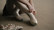 © Framestock - Adult ballerina sits on floor at dance studio and puts on pointe shoes before choreography lesson. Beautiful dancer prepares for performance or training. Classical ballet dance school. Feet close up.
