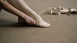 © Framestock - Ballerina sits on floor at dance studio and puts on pointe shoes before choreography lesson. Graceful ballet dancer prepares for performance or training. Classical ballet dance school. Feet close up.