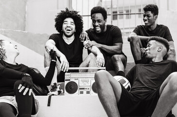 Group of multiracial people having fun listening music with vintage boombox stereo - Urban street people lifestyle - Black and white editing