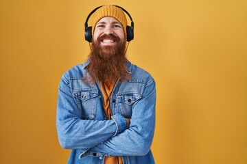 Poster - Caucasian man with long beard listening to music using headphones happy face smiling with crossed arms looking at the camera. positive person.