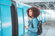 © oatawa - Happy young tourist African American woman with backpack and holding smartphone while at the train station and the train is arriving., Enjoying travel concept