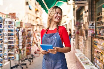 Sticker - Young hispanic woman shop assistant using touchpad at street