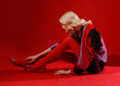 © Sergey Chumakov - fashionable woman in red dress and tights sitting on floor isolated on red background