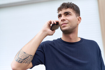 Canvas Print - Young hispanic man talking on smartphone with serious expression at street