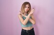 © Krakenimages.com - Blonde caucasian woman standing over pink background rejection expression crossing arms doing negative sign, angry face
