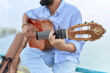 © Krakenimages.com - Young hispanic man musician playing classical guitar sitting on balustrade at seaside