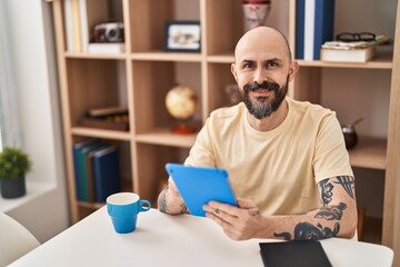 Wall Mural - Young bald man using touchpad sitting on table at home