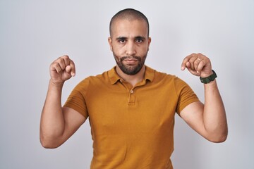 Poster - Hispanic man with beard standing over white background pointing down looking sad and upset, indicating direction with fingers, unhappy and depressed.