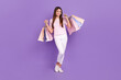 © deagreez - Full body photo of positive cheerful girl hands hold boutique bags isolated on violet color background