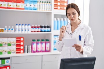 Poster - Young woman pharmacist reading prescription at pharmacy