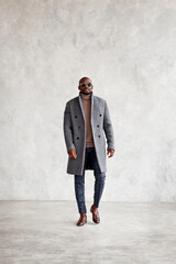 Wall Mural - Full length of handsome young man in turtleneck, gray coat, plaid trousers and leather loafer boots walking isolated on wall background, copy space. Fashion style for men