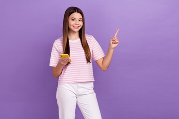 Poster - Photo of funny sweet girl dressed striped t-shirt writing modern device pointing empty space isolated purple color background