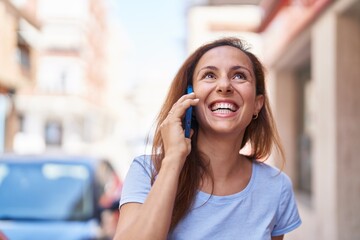 Wall Mural - Young woman smiling confident talking on the smartphone at street