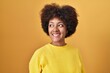 © Krakenimages.com - Young african american woman standing over yellow background looking away to side with smile on face, natural expression. laughing confident.