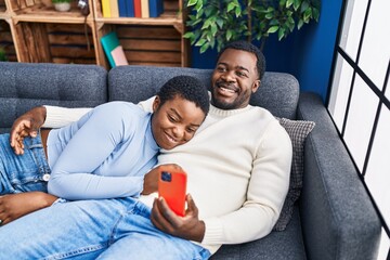 Sticker - Man and woman couple using laptop lying on sofa at home