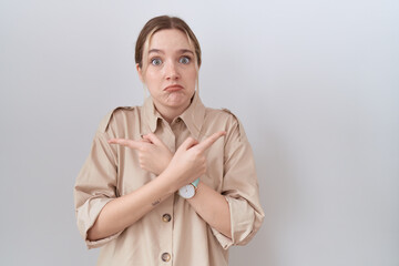 Young caucasian woman wearing casual shirt pointing to both sides with fingers, different direction disagree