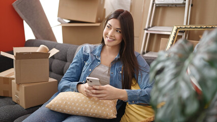 Poster - Young beautiful hispanic woman smiling confident using smartphone at new home