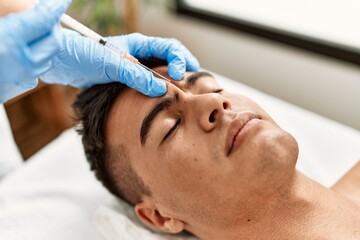 Wall Mural - Young hispanic man relaxed having antiaging treatment at beauty center