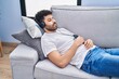 © Krakenimages.com - Young arab man listening to music sleeping on sofa at home