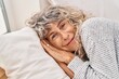 © Krakenimages.com - Middle age woman smiling confident lying on bed at bedroom