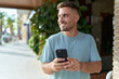 © Krakenimages.com - Young hispanic man smiling confident using smartphone at street