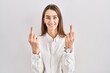Young caucasian woman standing over isolated background showing middle finger doing fuck you bad expression, provocation and rude attitude. screaming excited