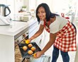 © Krakenimages.com - Hispanic brunette woman putting tray with cupcakes in the oven by kitchen oven