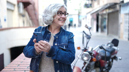 Poster - Middle age woman with grey hair using smartphone at street