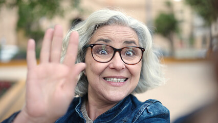 Poster - Middle age woman with grey hair smiling confident having video call at park