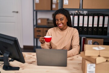 Wall Mural - African american woman ecommerce business worker using laptop drinking coffee at office