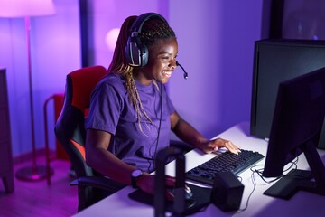 African american woman streamer playing video game using computer at gaming room