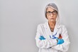© Krakenimages.com - Middle age woman with grey hair wearing scientist robe skeptic and nervous, disapproving expression on face with crossed arms. negative person.