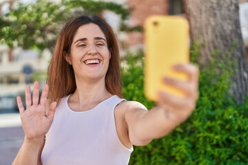 Wall Mural - Brunette woman taking a selfie photo with smartphone looking positive and happy standing and smiling with a confident smile showing teeth