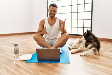 Canvas Print - Young hispanic man smiling confident having video call with dog at sport center