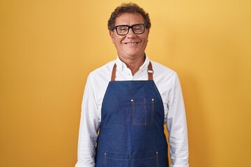 Middle age hispanic man wearing professional cook apron with a happy and cool smile on face. lucky person.