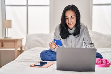 Poster - Young caucasian woman using laptop and credit card sitting on bed at bedroom