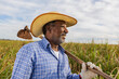 Black farmer smiling, with a hoe in his hands. Brazilian farmer. Family farming. Sugar cane. Closed plan.
