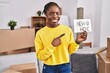 © Krakenimages.com - Beautiful black woman moving to a new home smiling happy pointing with hand and finger