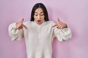 Canvas Print - Young south asian woman standing over pink background pointing down with fingers showing advertisement, surprised face and open mouth